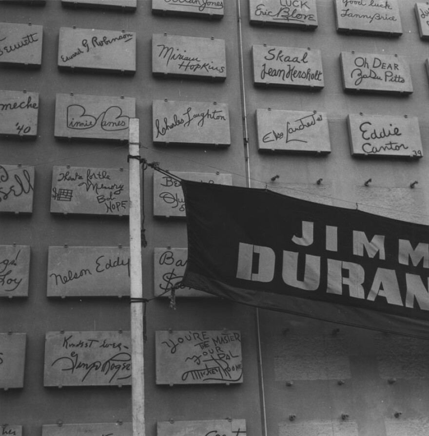 Exterior view of the Earl Carroll Theatre, circa 1940. Plaques feature signatures from some of the top performers of the day; from left to right: Edward G. Robinson, Miriam Hopkins, Jean Hersholt, Binnie Barnes, Charles Laughton, Elsa Lanchester, Bob Hope, Nelson Eddy, Ginger Rogers, and Mickey Rooney. A banner shows Jimmy Durante's name.