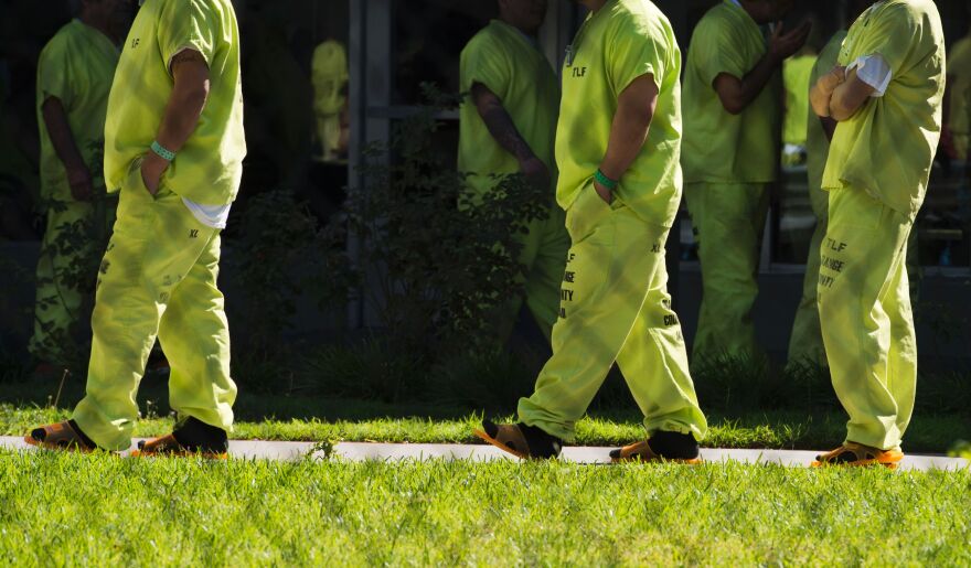 Men wearing neon-colored jail clothes signifying immigration detainees walk to pick up their lunches at the Theo Lacy Facility, a county jail which houses convicted criminals as well as immigration detainees, March 14, 2017 in Orange, California, about 32 miles (52km) southeast of Los Angeles.
US President Donald Trumps first budget provides more than USD 4.5 billion in new spending to fight illegal immigration by adding immigration and border enforcement agents, prosecutors and judges, as well as building a wall on the border with Mexico. / AFP PHOTO / Robyn Beck        (Photo credit should read ROBYN BECK/AFP/Getty Images)