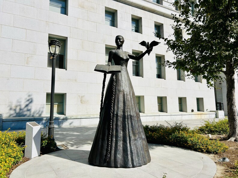 A statue of a female presenting woman with a dress, holding a bird.