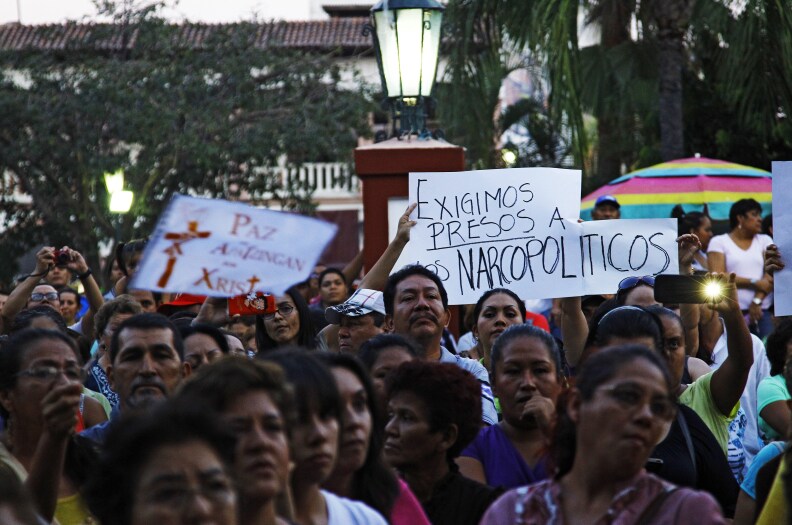 People hold a sign reading 'We demand narco-politicians to be jailed' as they take part in a march for peace in Apatzingan, Michoacan State, Mexico, on January 18, 2014. Federal forces in recent days have moved into Michoacan, in western Mexico, and tried to disarm the local vigilante groups and flush out the Knights Templar drug trafficking gang, which has seized control of large swathes of this state.