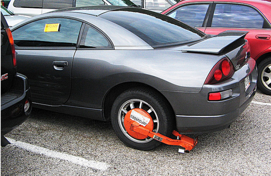 A impounded vehicle with a boot is seen in a tow yard. 
