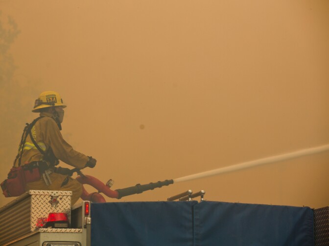 Firefighters fight flames from across Banyan Street using a hose on top of a fire truck as the Etiwanda Fire burns in Rancho Cucamonga on Wednesday, April 30, 2014.
