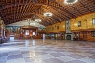 A large lodge has high ceilings, a stage and a large stone fireplace. 