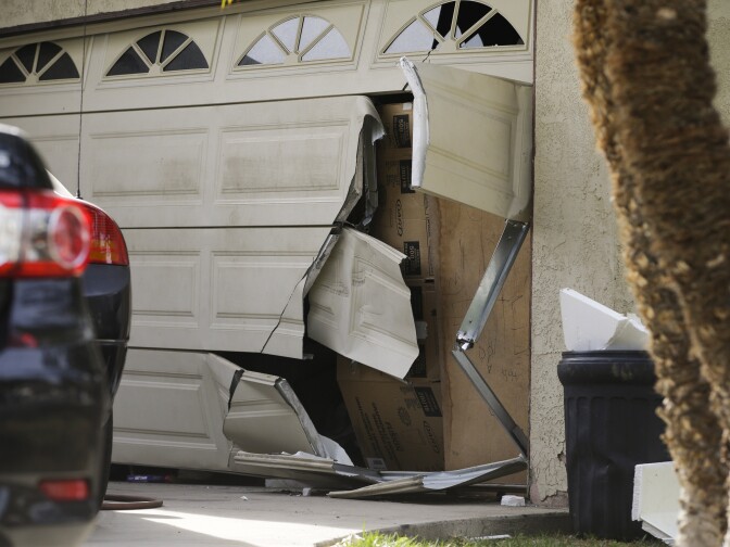 A garage door of Enrique Marquez's home is seen broken in a recent FBI raid, Wednesday, Dec. 9, 2015, in Riverside, Calif. Authorities have said Enrique Marquez, an old friend of San Bernardino attacker Syed Farook, purchased two assault rifles used in last week's fatal shooting that killed 14 people. 