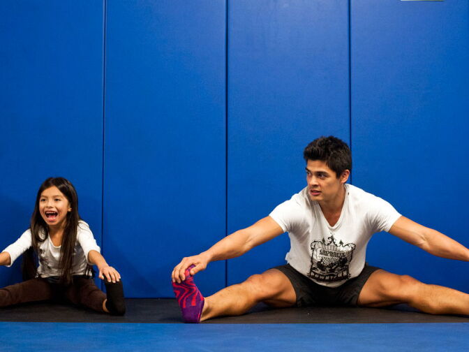 Seven-year-old Perla Bazaldua, left, stretches with PAL Fit coach Ron Teasdale during a CrossFit Tuesdays class on Dec. 11 in the underground parking garage at the Newton Police Station. The class is free for local kids, and is a part of the Police Activity League, a crime prevention program for community youth.