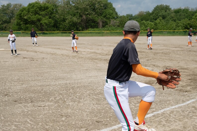 少年野球チームのメンバーが練習しています。 前の選手がチームメイトに投げる準備をしています。