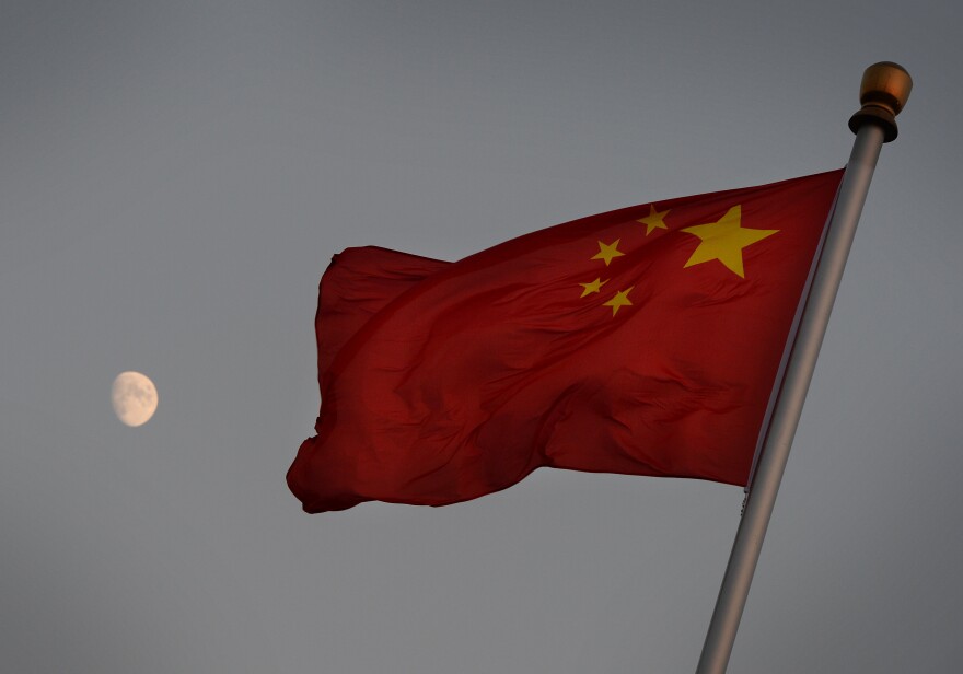 The Chinese flag is seen in front of a view of the moon at Tiananmen Square in Beijing on December 13, 2013. China's first lunar rover which entered the moon's orbit last week is expected to makes it's planned landing on the moon's surface on December 14. The rover known as Yutu, or Jade Rabbit will explore its surface and search for natural resources. 