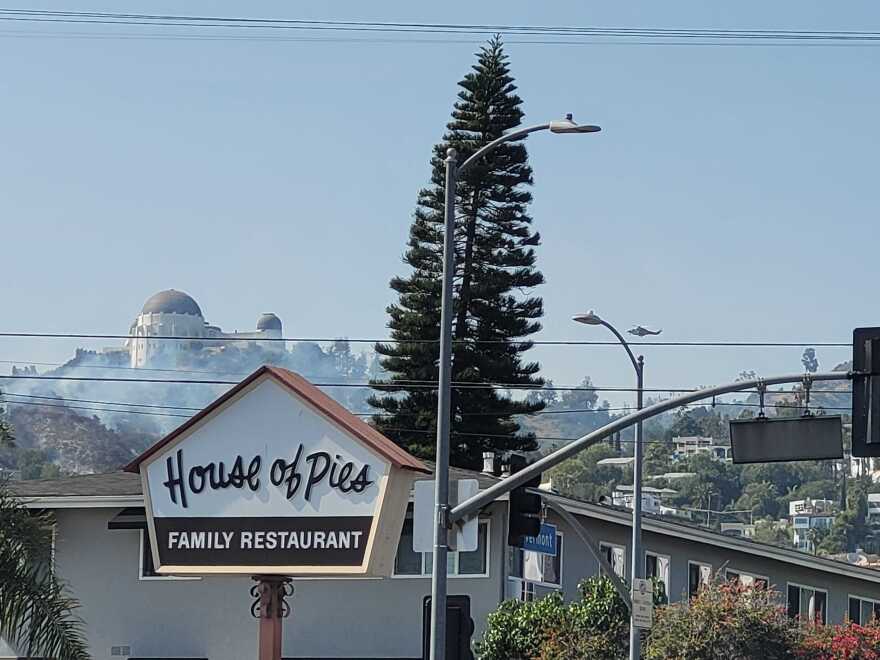 Smoke rises near the Griffith Observatory behind the "House of Pies" sign in Los Feliz