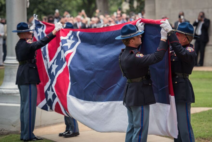 TOPSHOT - Members of the Mississippi Highway Safety Patrol Honor Guard retire the state flag outside the Mississippi State Capitol building in Jackson, Mississippi on July 1, 2020. - Mississippi's flag, the last US state banner to feature a Confederate emblem, was permanently retired Wednesday when it was lowered from the state's capitol and removed from the grounds. The move comes one day after Governor Tate Reeves signed a bill ordering the rebel-themed flag's removal, which comes in the wake of coast-to-coast protests over the police killing of African American George Floyd in May. (Photo by Rory Doyle / AFP) (Photo by RORY DOYLE/AFP via Getty Images)