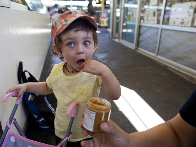 Giya Raju, 1, tastes the trail mix nut butter from Magee's at the Farmers Market in Los Angeles. She traveled to California with her mother, Sylvia, from Victoria, Canada, and visited the market for the first time on their trip.