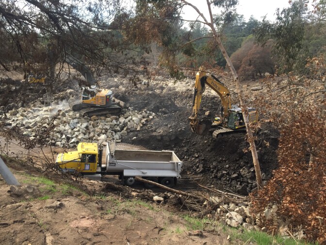 To clear the basin of boulders, crews are using three machines. One moves the rocks towards the second one, which breaks them into smaller rocks. The third loads up trucks to take them away.