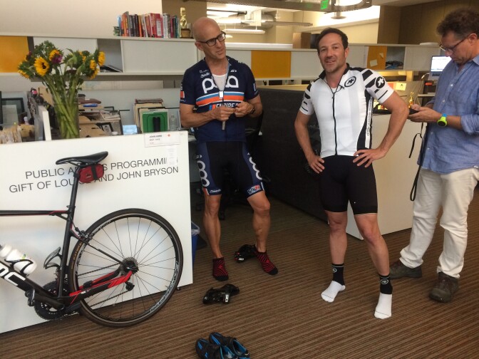 The Frame's John Horn & filmmaker Bryan Fogel get outfitted with audio gear before recording an interview while riding bikes through Pasadena. 