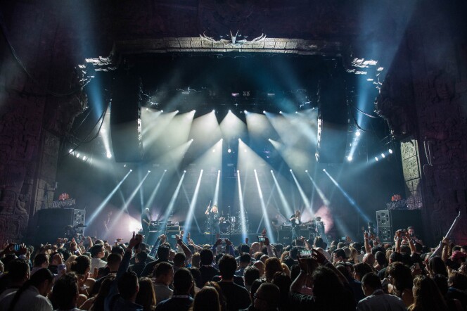 A musical group performs to a crowd inside a theater.
