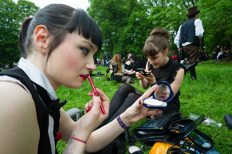 LEIPZIG, SAXONY - MAY 17:  Two girls in black clothing refresh their make-up during the traditional park picnic on the first day of the annual Wave-Gotik Treffen, or Wave and Goth Festival, on May 17, 2013 in Leipzig, Germany. The four-day festival, in which elaborate fashion is a must, brings together over 20,000 Wave, Goth and steam punk enthusiasts from all over the world for concerts, readings, films, a Middle Ages market and workshops.  (Photo by Marco Prosch/Getty Images)