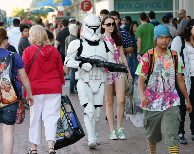 Myke Soler (C) of California walks outside the San Diego Convention Center dressed as a clone trooper from the "Star Wars" movie franchise with his wife Kimberly Soler during Comic-Con International 2013 on July 17, 2013 in San Diego, California.