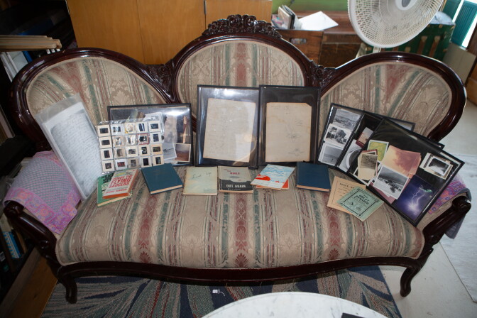 A Victorian style sofa displayed with photos and documents. 