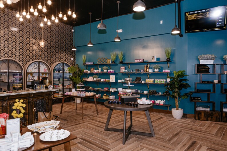 a store with one dark blue wall, another wall with ornate black and gold wallpaper and shelves and tables stocked with products