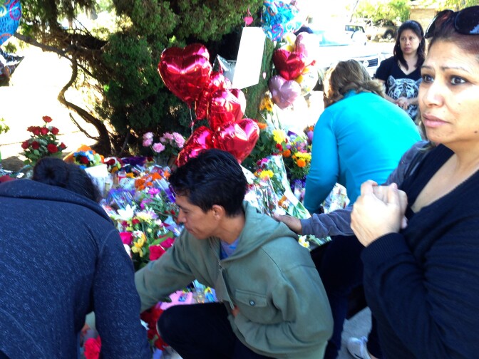 Stepfather Juan Pablo Ramirez (center) briefly visited the memorial to drop off a pink donation box and framed elementary school graduation photos of the girls in their caps and gowns