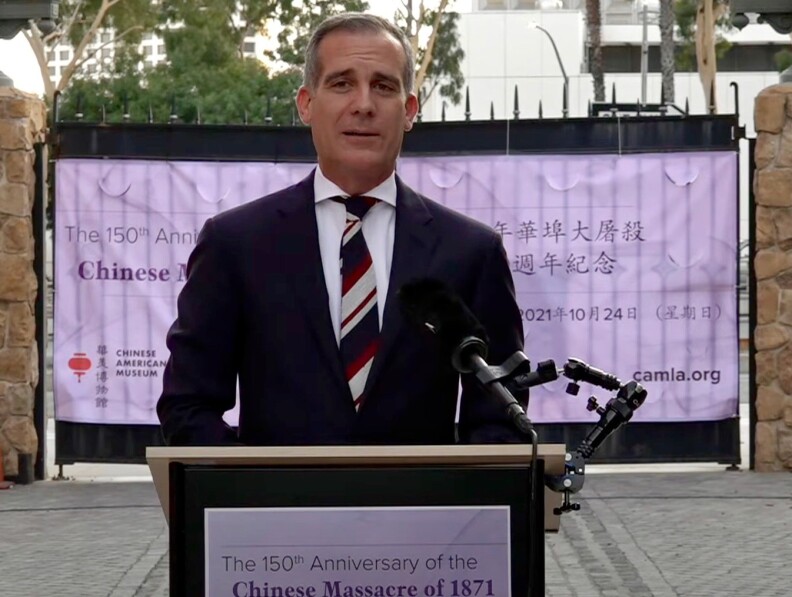 L.A Mayor Eric Garcetti speaks in front of a podium set outdoors.