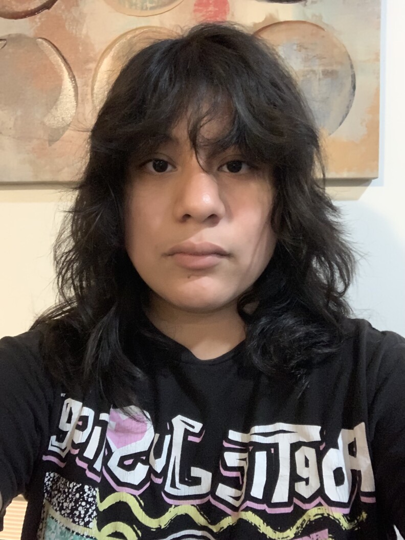 A young woman with light brown skin looks into the camera.