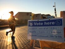 A jogger on The Stand, a beachfront walkway, passes a directional sign to a polling place in a Lifeguard Station at sunrise during the U.S. presidential election on November 6, 2012 in the Los Angeles area community of Hermosa Beach, California.
