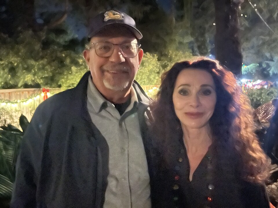 A man in a man and glasses. And a woman with wavy hear standing next to each other.