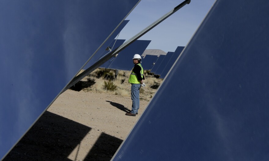 Noel Hanson stands near some of 300,000 computer-controlled mirrors that reflect sunlight to boilers that sit on 459-foot towers near a boilers that sit on 459-foot towers Tuesday, Feb. 11, 2014 in Primm, Nev. The Ivanpah Solar Electric Generating System, sprawling across roughly 5 square miles of federal land near the California-Nevada border, will be opened formally Thursday after years of regulatory and legal tangles. (AP Photo/Chris Carlson)