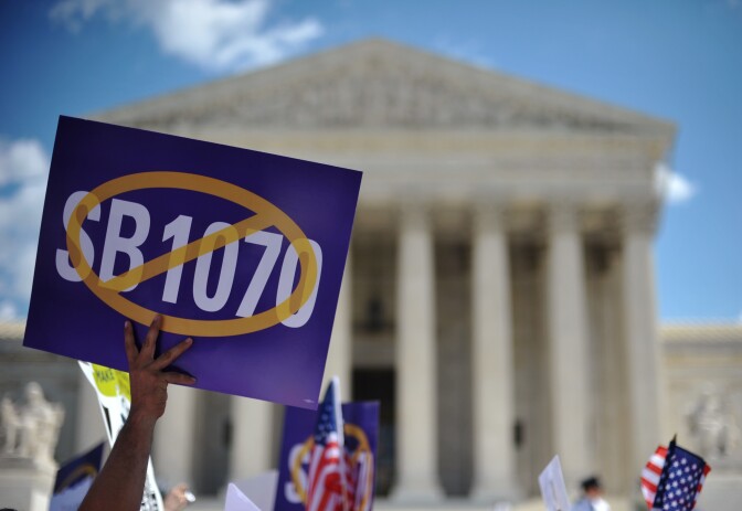 A protester holds a placard during a protest against Arizona Senate Bill 1070 on April 25, 2012 outside of the US Supreme Court in Washington, DC. The Supreme Court began reviewing Arizona's controversial law which empowers Arizona police officers to stop and demand papers of anyone suspected of being an illegal immigrant.