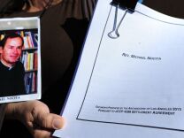 Esther Miller holds a picture and the released documents on Reverand Michael Nocita as victims and their supporters hold quilts bearing portraits of abused children while gathered outside the Cathedral of Our Lady of the Angels in Los Angeles, California, on February 1, 2013, one day after the release of personnel files of priests accused of sexual misconduct. The archbishop of Los Angeles Jose Gomez stripped his predecessor, retired Cardinal Roger Mahony, of all church duties on January 31. In all, 124 files were released on the Los Angeles archdiocese's website, listed by priests' names, including 82 containing information on allegations of childhood sexual abuse.