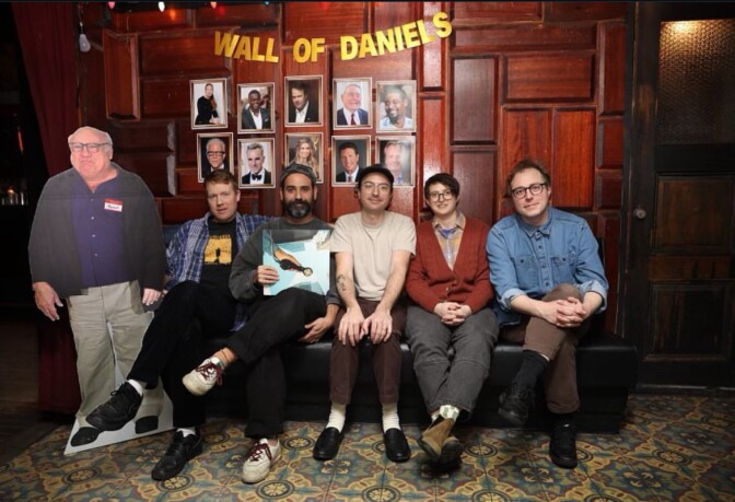 The band members of 'Real Estate' sit on a couch together holding their new album next to cut out of actor Danny Devito.