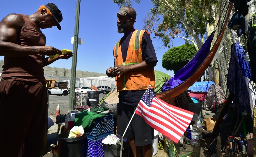 Homeless veteran Kendrick Bailey (C) has General Dogon (L) looks over some citations he recently received outside his tent on a streetcorner near Skid Row in downtown Los Angeles, California on June 20, 2017. 
Born and raised in the streets of Los Angeles Skid Row, General Dogon is a community organizer with the Los Angeles Community Action network (LACAN), whose mission is to help people dealing with poverty create and discover opportunities while serving to ensure the homeless have a voice, power and opinion in decisions directly affecting them. After dropping some 30 percent from 2015 to 2016, the population of homeless veterans living on Los Angeles streets increased in the official 2017 count to 4,828 from 3,071.   / AFP PHOTO / FREDERIC J. BROWN / With AFP Story by Veronique DUPONT:   Ranks of homeless veterans keep swelling in Los Angeles        (Photo credit should read FREDERIC J. BROWN/AFP/Getty Images)