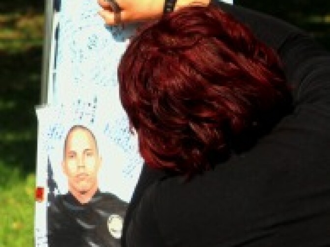 An unidentified woman writes a message at a memorial for Bonaminio in Fairmount Park in Riverside. 