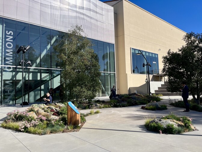 Glass and concrete building with trees and grass in front.