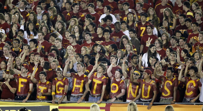 Fans cheer with their chests painted in the student section of the Los Angeles Memorial Coliseum during an NCAA college football game between Southern California and Virginia in Los Angeles on Saturday, Sept. 11, 2010. (AP Photo/Danny Moloshok)