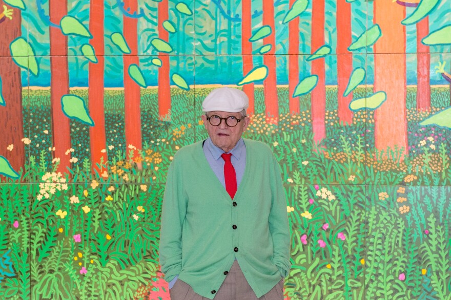 David Hockney poses in front of his painting "The Arrival Of Spring in Woldgate, East Yorkshire in 2011" at Centre Pompidou on September 26, 2017 in Paris, France.