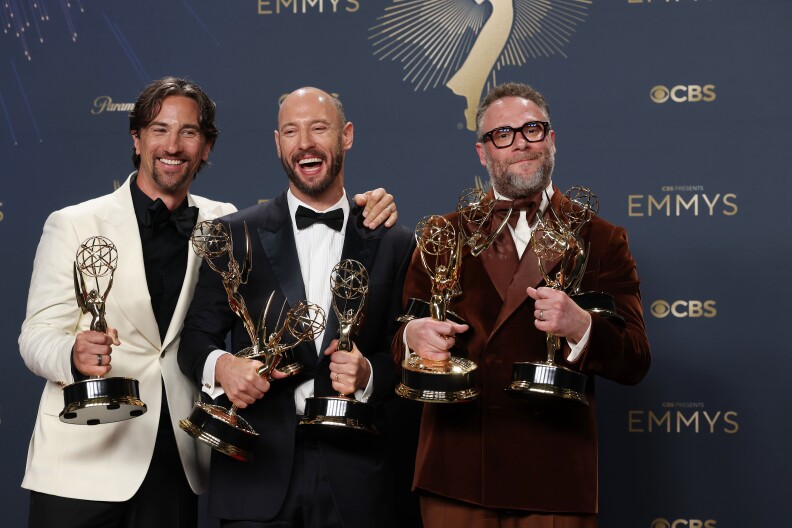 three men standing with trophies