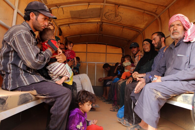 In this Thursday, Sept. 10, 2015 photo,  Syrian refugees sit in a Jordanian army vehicle after crossing into Jordanian territory with their families, in the Roqban reception area, near the northeastern Jordanian border with Syria, and Iraq, near the town of Ruwaished, 240 km (149 miles) east of Amman. The United Nations' refugee agency has urged Jordan to speed up security vetting for Syrian refugees, who must wait for weeks in a remote desert area during the process. (AP Photo/Raad Adayleh)