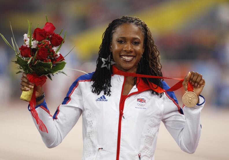 Britain's bronze medalist Tasha Danvers smiles for the camera as she holds up a bouquet of roses and her bronze medal.