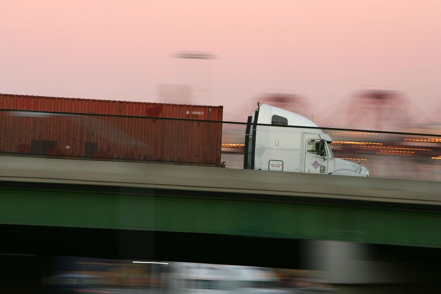 LONG BEACH, CA - JULY 06: A truck carries a shipping container at the ports of Long Beach and Los Angeles on July 6, 2006 in Long Beach, California. In the Los Angeles area, studies indicate that diesel exhaust from trucks, locomotives, heavy equipment and ships causes cancer and is responsible for 70% of pollution-related health problems and hundreds of deaths every year. Rather than wait for the international agency that regulates the global shipping industry, the International Maritime Organization, to implement considered changes to strengthen emissions standards for cargo vessels, the ports recently unveiled an ambitious clean-air plan that could significantly improve air quality. The proposal seeks to reduce diesel emissions from cargo ships, trains and trucks by more than 50% over a five-year period at a cost of $2-billion.Almost 5,800 ships called at the ports of Los Angeles and Long Beach in 2005 released about 14,000 tons of air pollutants. Many ships emit as much exhaust per day as 12,000 cars. (Photo by David McNew/Getty Images)