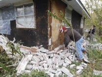 Chad Devereaux examines bricks that fell from three sides of his in-laws home in Sparks, Okla., following two earthquakes that hit the area in less than 24 hours. A study published Thursday, July 3, 2014 by the journal Science explains how just four wells forcing massive amounts of drilling wastewater into the ground are probably causing quakes in Oklahoma. The wells seem to have triggered more than 100 small-to-medium earthquakes in the past five years, according to a study.