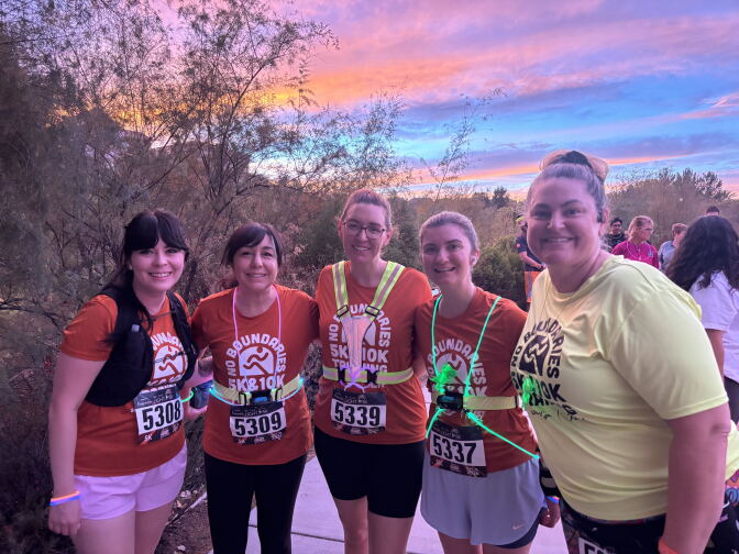 An early sunset is seen in the background during the "Be The Light" 5K event in Valencia last night. Five people gather a photo. Four wear red shirts, one wears a yellow shirt.