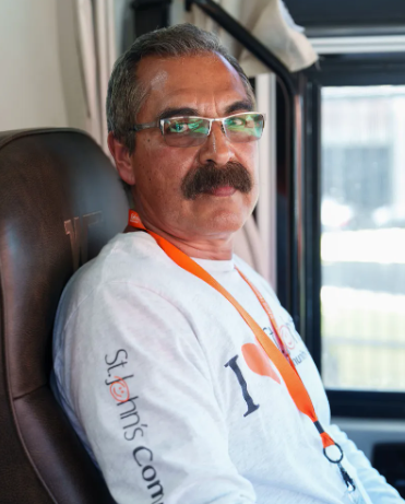 A man is sitting back in a leather chair wearing a white shirt and glasses.