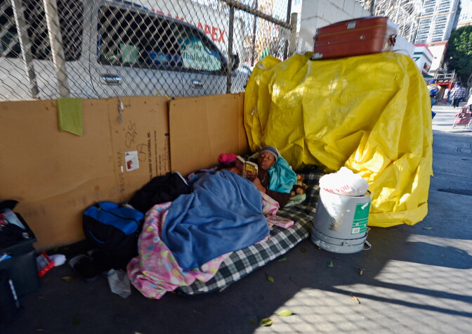 LOS ANGELES, CA - DECEMBER 11:  Homeless people from Skid Row are seen on the streets around a construction project where102 prefabricated housing units placed on top of the second floor of Star Apartments are being built December 11, 2012 in Los Angeles, California. The modular homes will become the first multi unit prefabricated homes in Los Angeles for formerly homeless and impoverished people. Despite efforts from the Federal Government and local officials to provide more shelters and beds for homeless people, the number of people living on the streets remained unchanged from January 2011 to January 2012. The number of homeless families increased while the number of veterans on the street decreased.  (Photo by Kevork Djansezian/Getty Images)