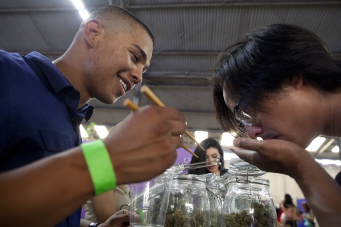 Anthony Guillen, left, shows a sample of a marijuana bud to a patient at the California Heritage Market, the first-ever cannabis farmers market in Los Angeles. The event drew more than a thousand people to an industrial area of Boyle Heights where all types and forms of marijuana were for sale to medical marijuana patients.