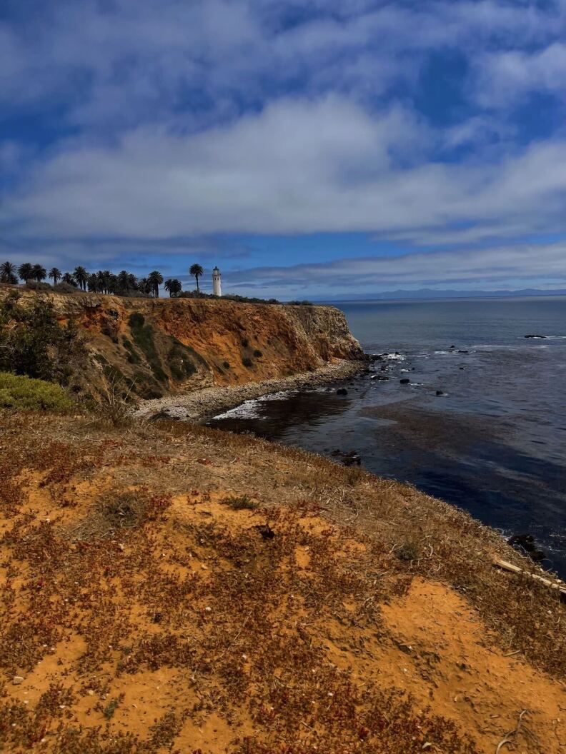 A picture of a beach with a lighthouse in the distance.