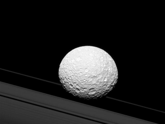 It may look as though Saturn's moon Mimas is crashing through the rings in this image taken by NASA's Cassini spacecraft, but Mimas is actually 28,000 miles away from the rings. The gravitational pull of Mimas (246 miles across) creates waves in Saturn's rings that are visible in some Cassini images. The image was taken in green light with Cassini's narrow-angle camera on Oct. 23, 2016. The view was acquired at a distance of approximately 114,000 miles from Mimas.