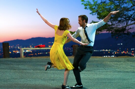 Emma Stone and Ryan Gosling dance on a hilltop with a scenic view of Los Angeles in the background in the film "La La Land." 