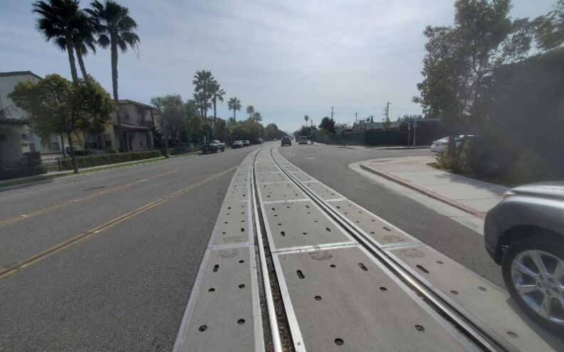 The scene is a typical Southern California street, with palm trees off in the background: But the street is exceptionally wide, and there are old train tracks running down the middle of the road, a hint of what this place used to be.