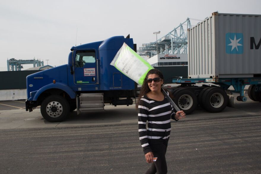 Gina, a clerical worker at the Port of Los Angeles, pickets in front of a truck that cannot enter the APM terminal due to the ongoing strike. L.A. Mayor Antonio Villaraigosa says the strike is costing the local economy billions.