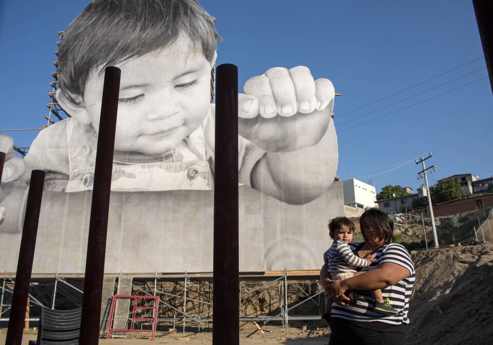 Lissy and her son Enrique Achondo, who was pictured by French artist JR for his artwork, poses for a picture on the Mexican side of the US - Mexico border where the giant print of Enrique has been installed in Tecate, Baja California, Mexico on September 6, 2017.
